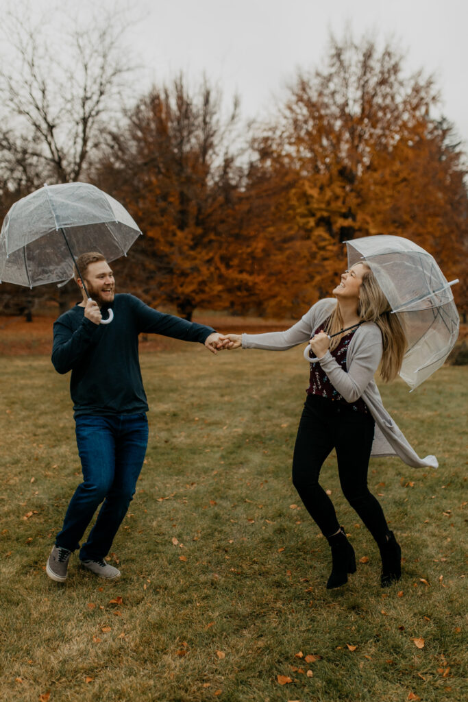 rainy engagement photos for a couple holding umbrellas running around in the rain 