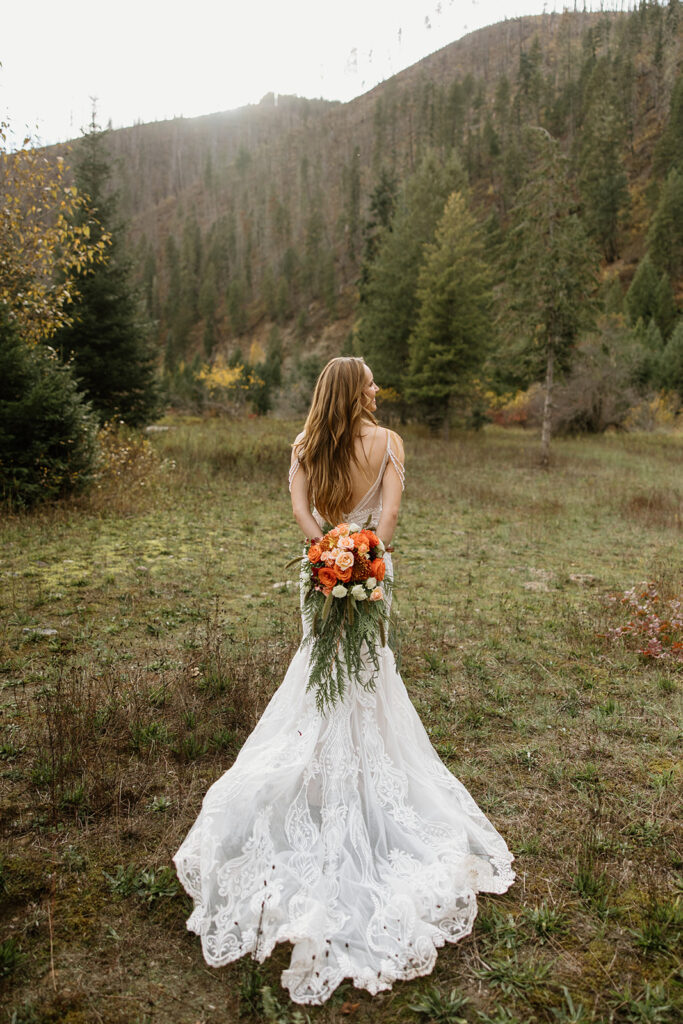 Bride holding bouquet behind her in the mountains