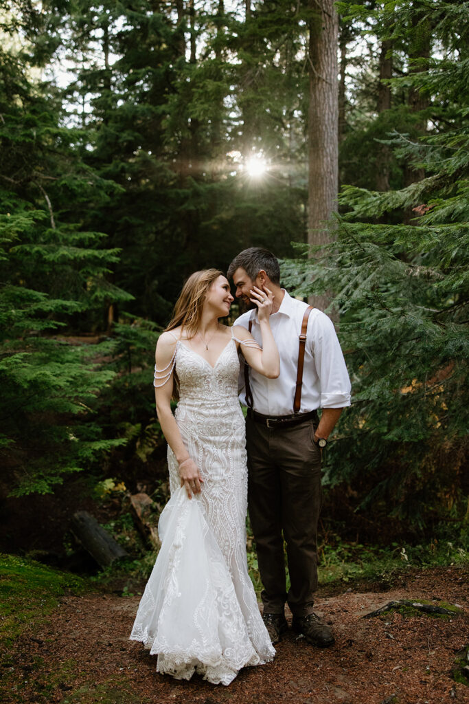 bride caressing groom in the forest during their elopement photos