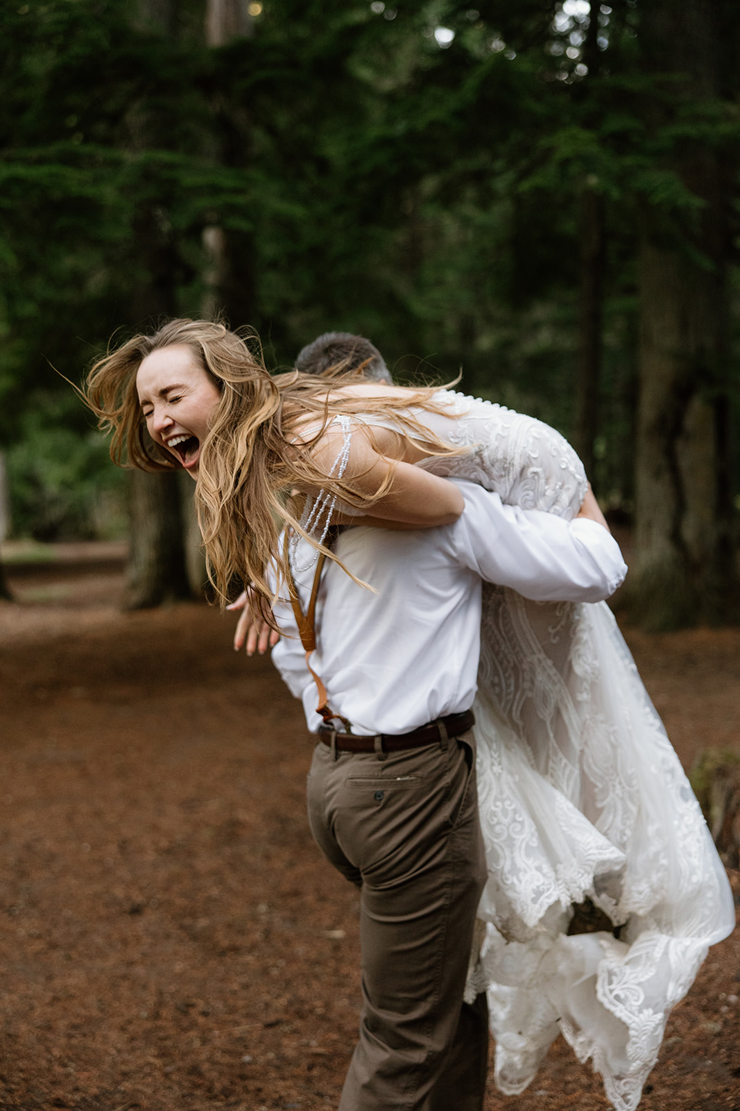 groom running into the woods while carrying his bride during their elopement photos