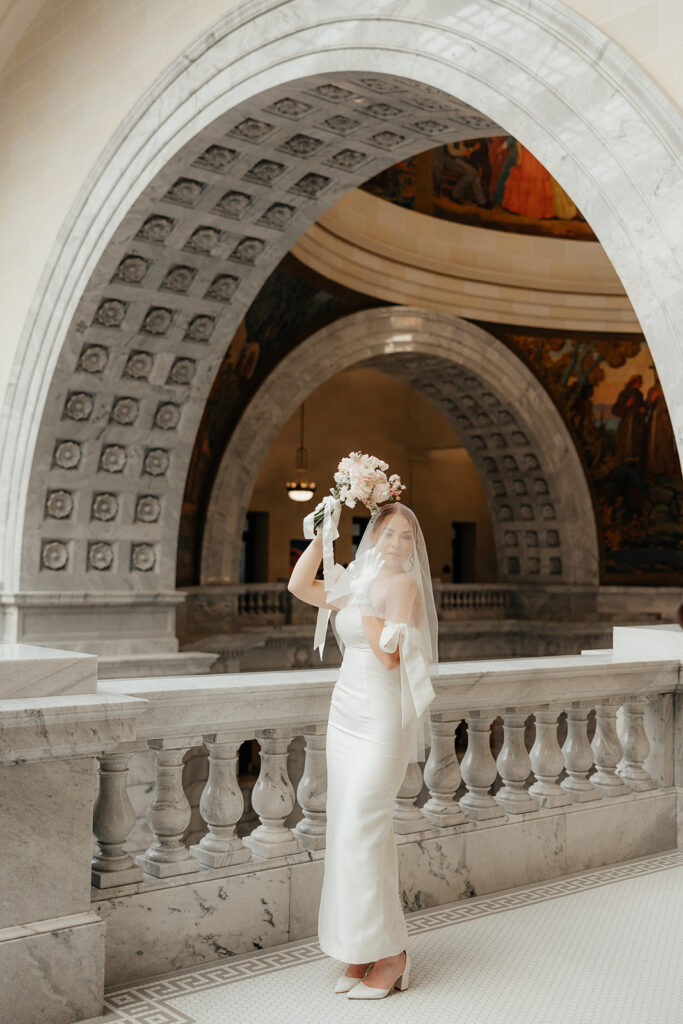 Bride holding bouquet and wearing a vail in the Utah State Capitol